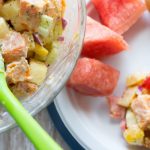 image of super sweet potato salad by intentionally eat with Cindy Newland in a glass bowl with a green spoon a plate with watermelon next to it