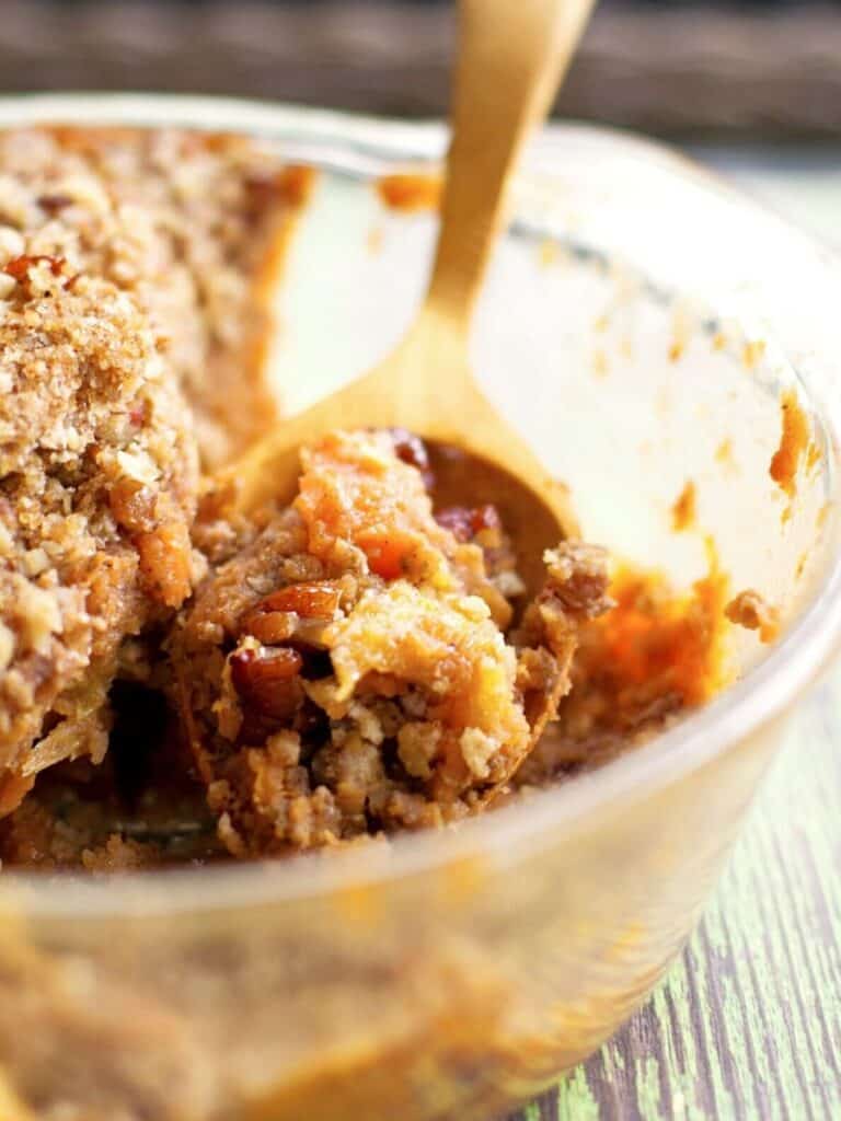 eggless sweet potato casserole in a glass dish with a wooden spoon