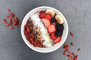 a white bowl filled with oats, bananas, blackberries, strawberries and goji berries