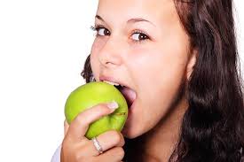 woman taking a bite out of a granny smith apple