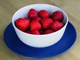 image of strawberries in a white bowl sitting on a blue plate