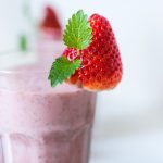 Image of glass holding Berry Blast smoothie by Intentionally Eat. The glass has a strawberry on the lip. Image for 5 healthy non-dairy smoothies by intentionally eat