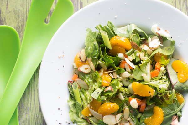 image of Easy Mandarin Salad Recipe by Intentionally Eat with Cindy Newland in a white bowl with green salad tossers 