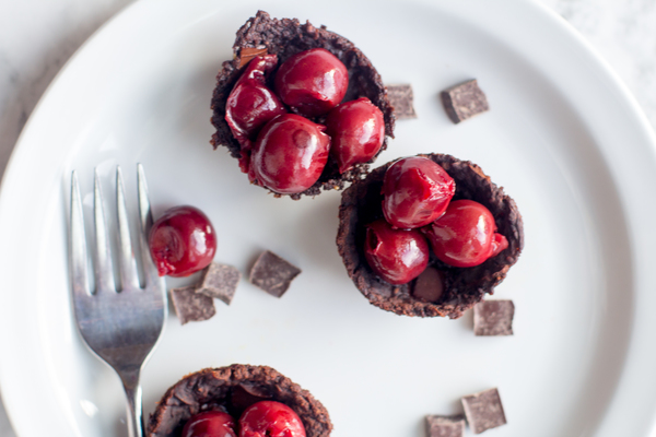 125 Calorie Flourless Chocolate Cake by Intentionally Eat topped with cherries on a plate with a fork and chocolate chunks