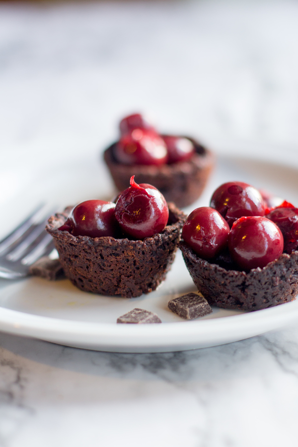image of 125 Calorie Flourless Chocolate Cake by Intentionally Eat topped with cherries on a plate with a fork
