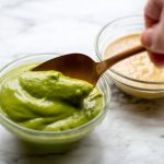 image of cilantro dipping sauce by intentionally eat being spooned out of a glass bowl