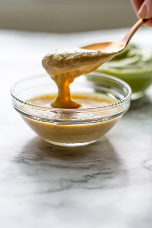 image of spicy peanut dipping sauce by intentionally eat being spooned out of a glass bowl.