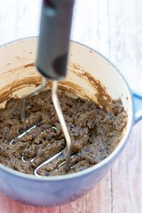 image of easy healthy refried beans by cindy newland with intentionally eat in a blue pot with a masher