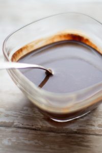image of easy dairy free hot fudge sauce by cindy newland with intentionally eat in a glass bowl with a silver spoon in it