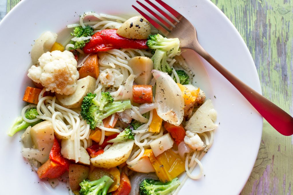 image of pasta with sauteed vegetables on a white plate with a fork