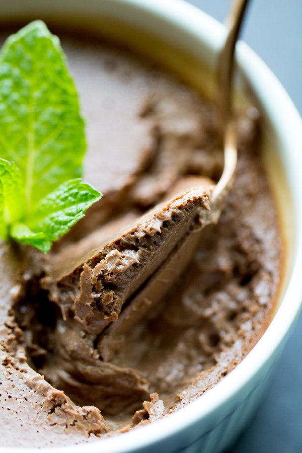 image of Mint Chocolate Pots de Creme by Cindy Newland with Intentionally Eat in a white bowl with a spoon and a mint leaf