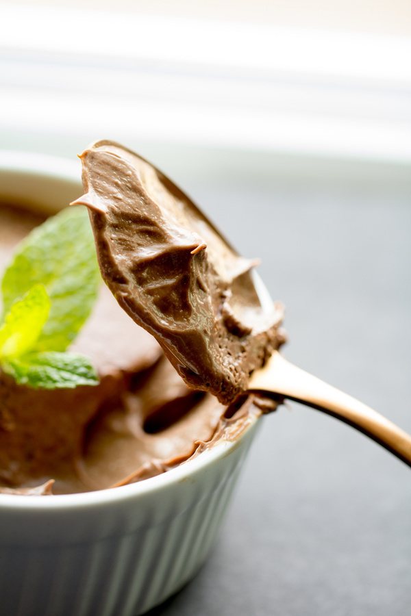 image of Mint Chocolate Pots de Creme by Cindy Newland with Intentionally Eat in a white bowl with a spoon and a mint leaf