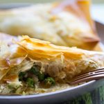 image of Easy Air Fried Vegetable Samosas by Cindy Newland with Intentionally Eat filled with spicy potato and pea filling served with cilantro dipping sauce on a plate with a gold fork