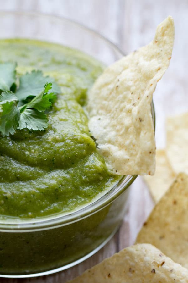 green salsa verde in a glass bowl with cilantro and tortilla chips