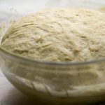 The Best Homemade Pizza Dough by Intentionally Eat with Cindy Newland in a clear glass bowl