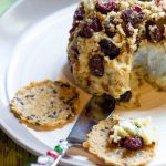 image of cranberry crusted dairy free cheese ball by Intentionally Eat with Cindy Newland on a plate with a cracker