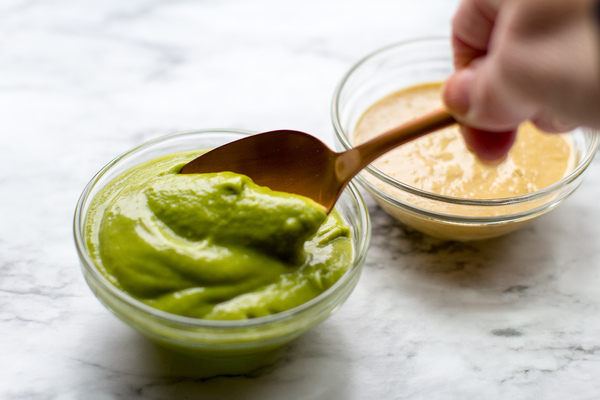 photo of cilantro dipping sauce in a glass bowl with a gold spoon. A bowl of spicy peanut sauce is in the background
