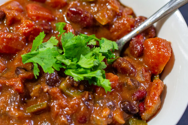 image of black bean pumpkin chili by Intentionally Eat with Cindy Newland in a white bowl with a spoon
