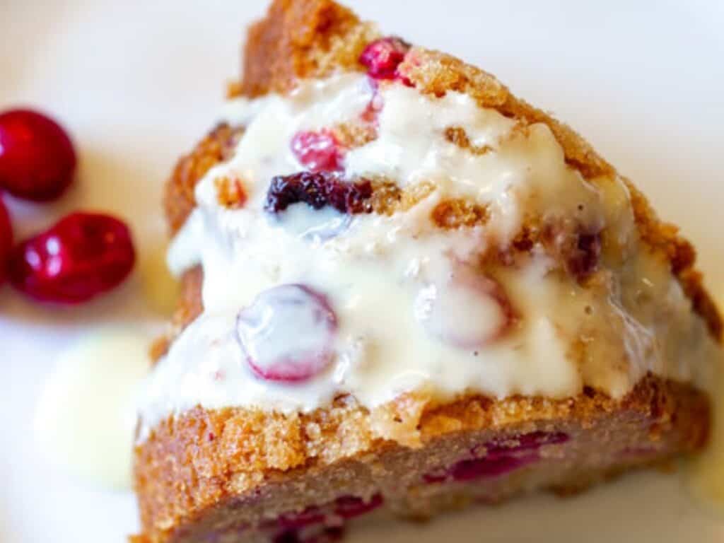 a slice of vegan cranberry Christmas cake on a white plate