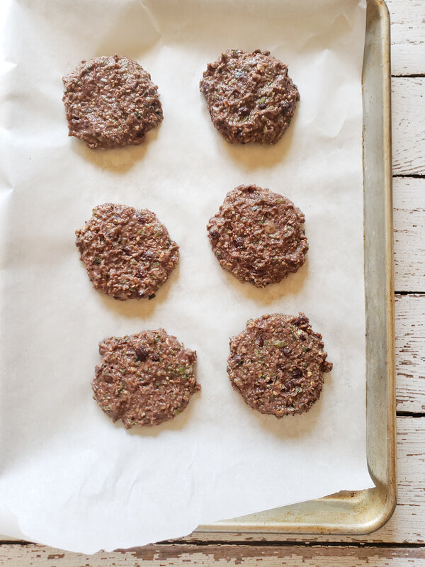 photo of six black bean burger patties on a parchment lined cookie sheet