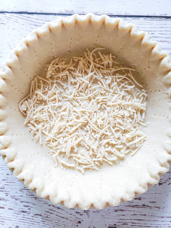 image of pie crust pricked by a fork with dairy-free cheese sprinkled over it
