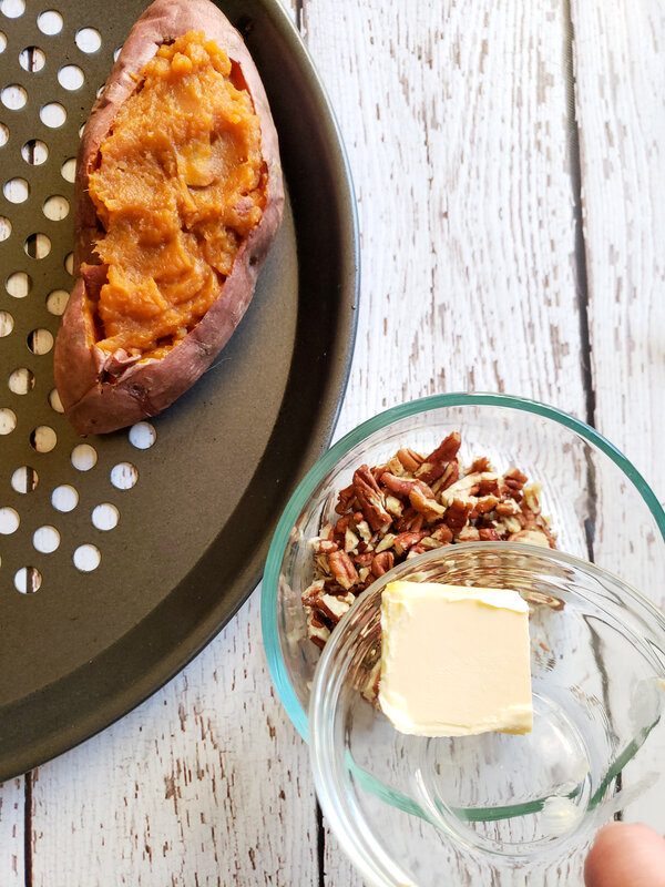 image of a stuffed sweet potato and a bowl of chopped pecans.  A hand is holding a glass bowl with vegan butter in it