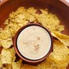 image of easy vegan queso dip in a white bowl surrounded by tortilla chips