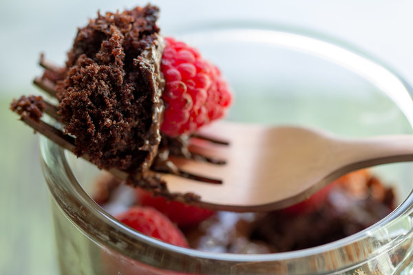 vegan chocolate cake with raspberries on a fork balancing on the mug