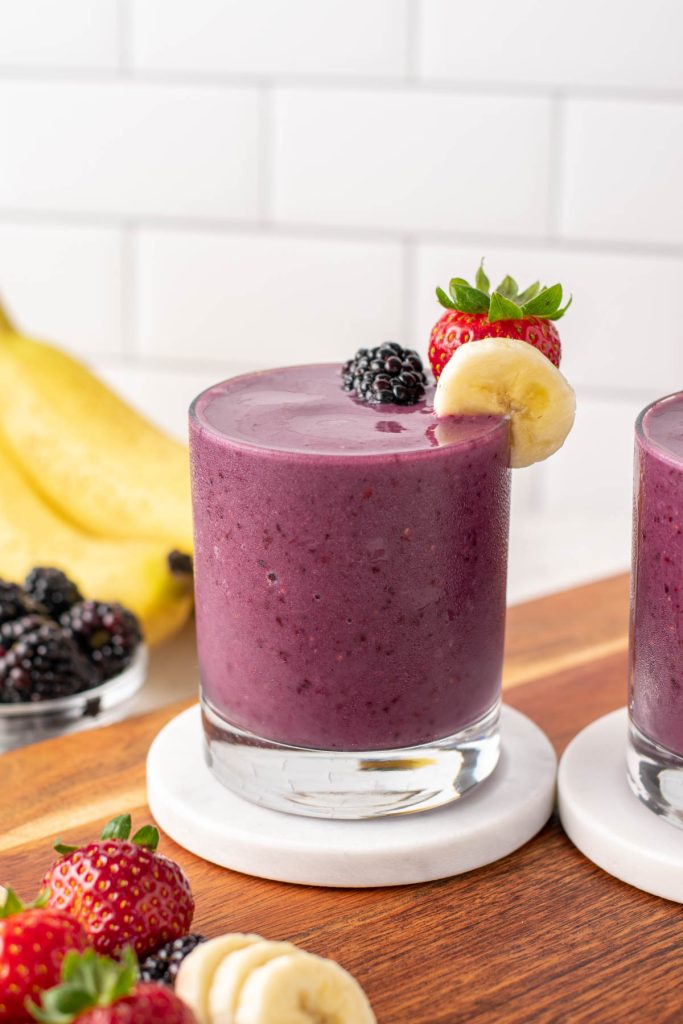 healthy smoothie in a glass with banana and berries on top