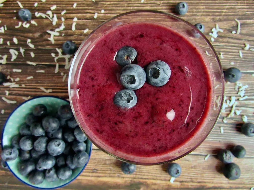 blueberry coconut vegan smoothie in a glass topped with blueberries