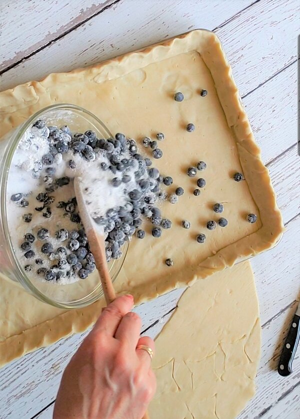 spreading blueberry pie filling into crust
