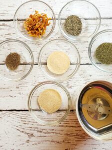 assorted spices in bowls with a spice grinder