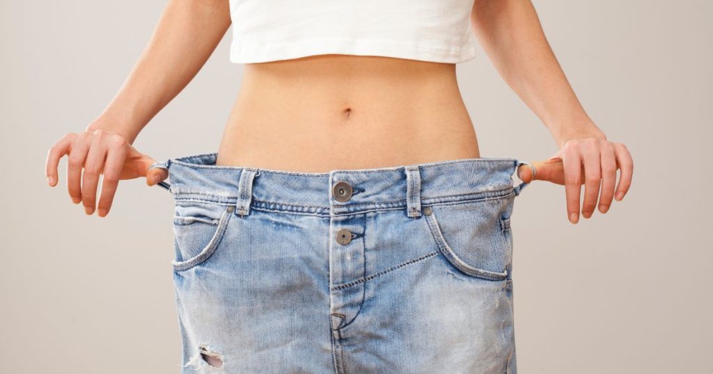 image of woman with thumbs in her pant loops holding jeans away from her waist