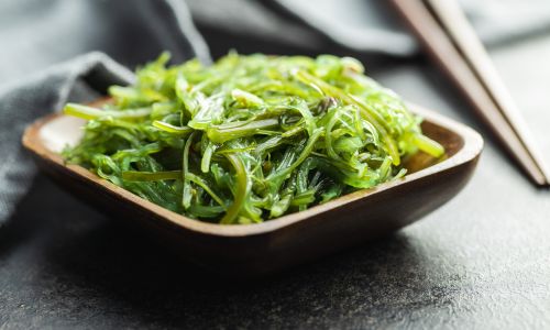 seaweed salad in a bowl with chopsticks next to it