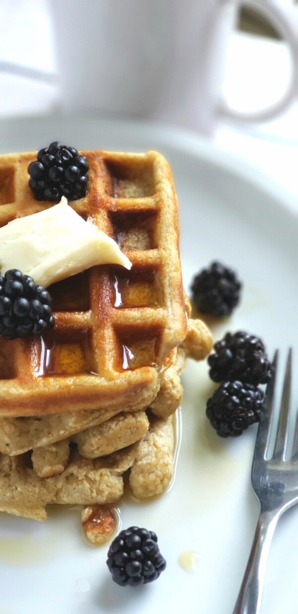 a stack of vegan waffles with dairy free butter and blackberries