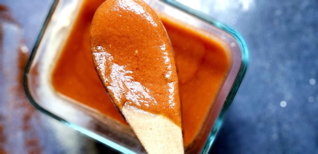 a wooden spoon with enchilada sauce on it