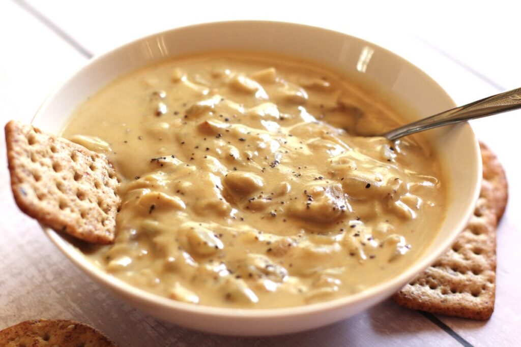 bowl of dairy free mushroom soup with a spoon and crackers