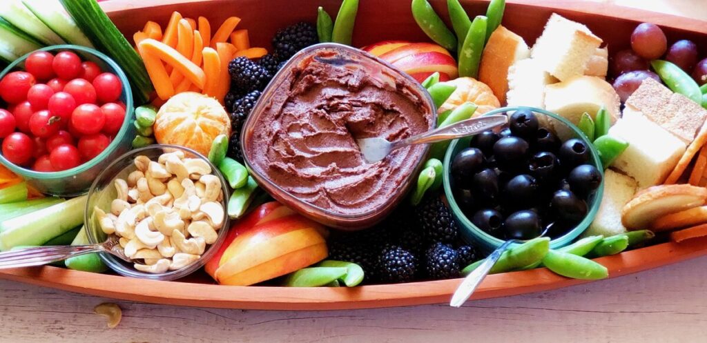 vegetarian charcuterie board with bean dip, olives, tomatoes, carrots, and more