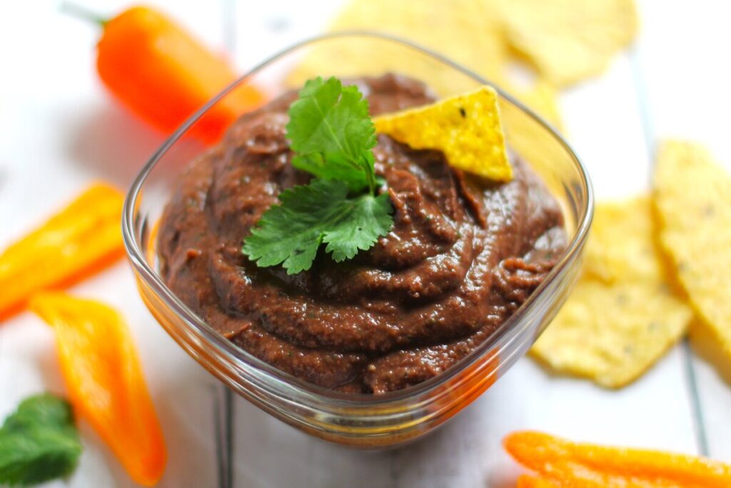 black bean dip in a glass bowl with peppers and tortilla chips