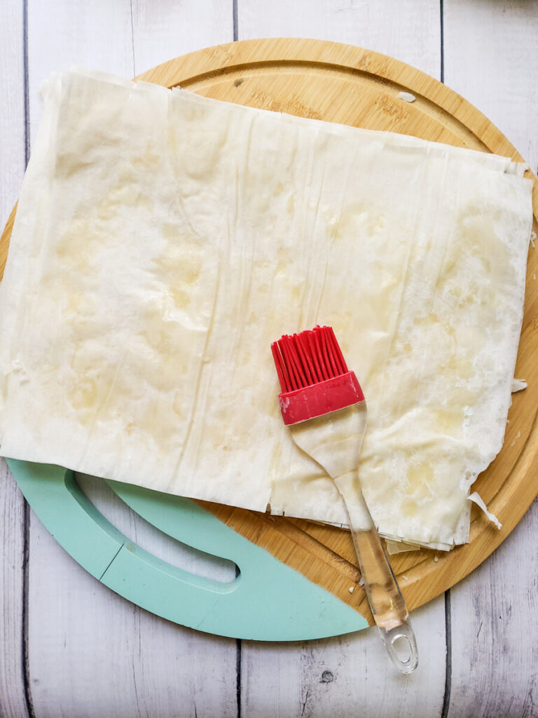 phyllo sheets on a cutting board with a brush
