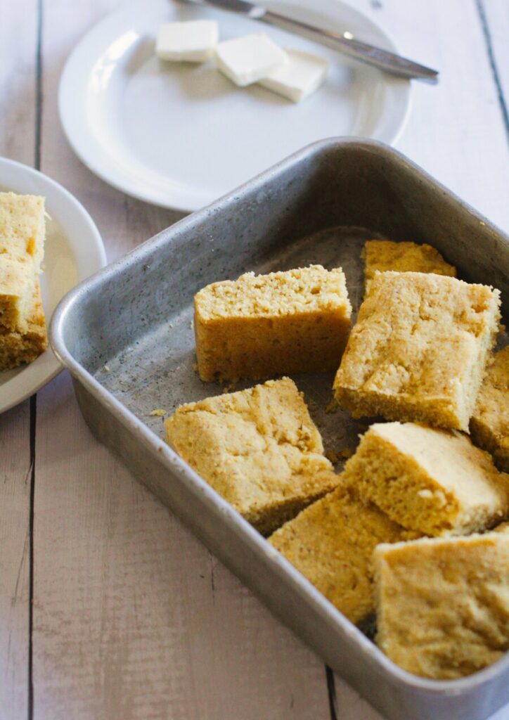 cornbread in a baking pan with pats of vegan butter