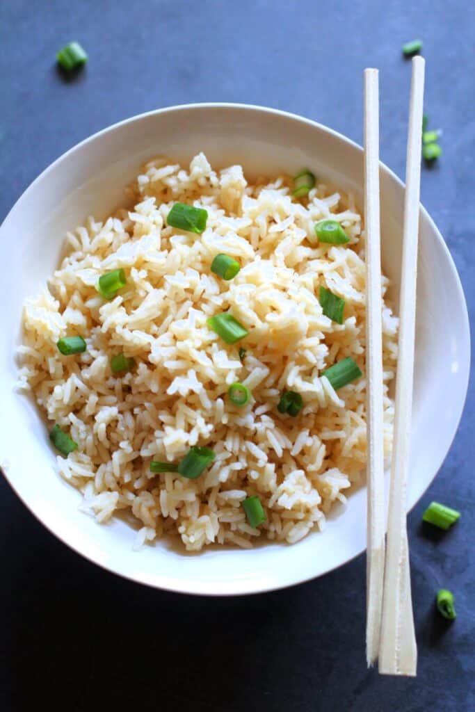 long grain rice in a white bowl with chopsticks