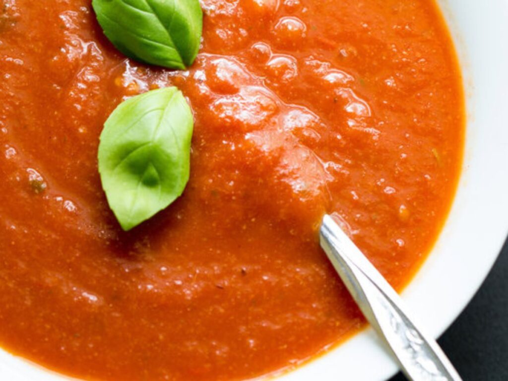 a bowl of tomato soup with fresh basil