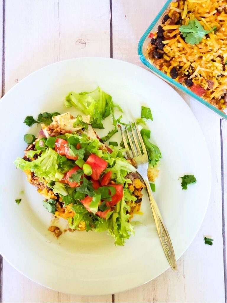 taco salad casserole on a plate with a casserole dish in the background