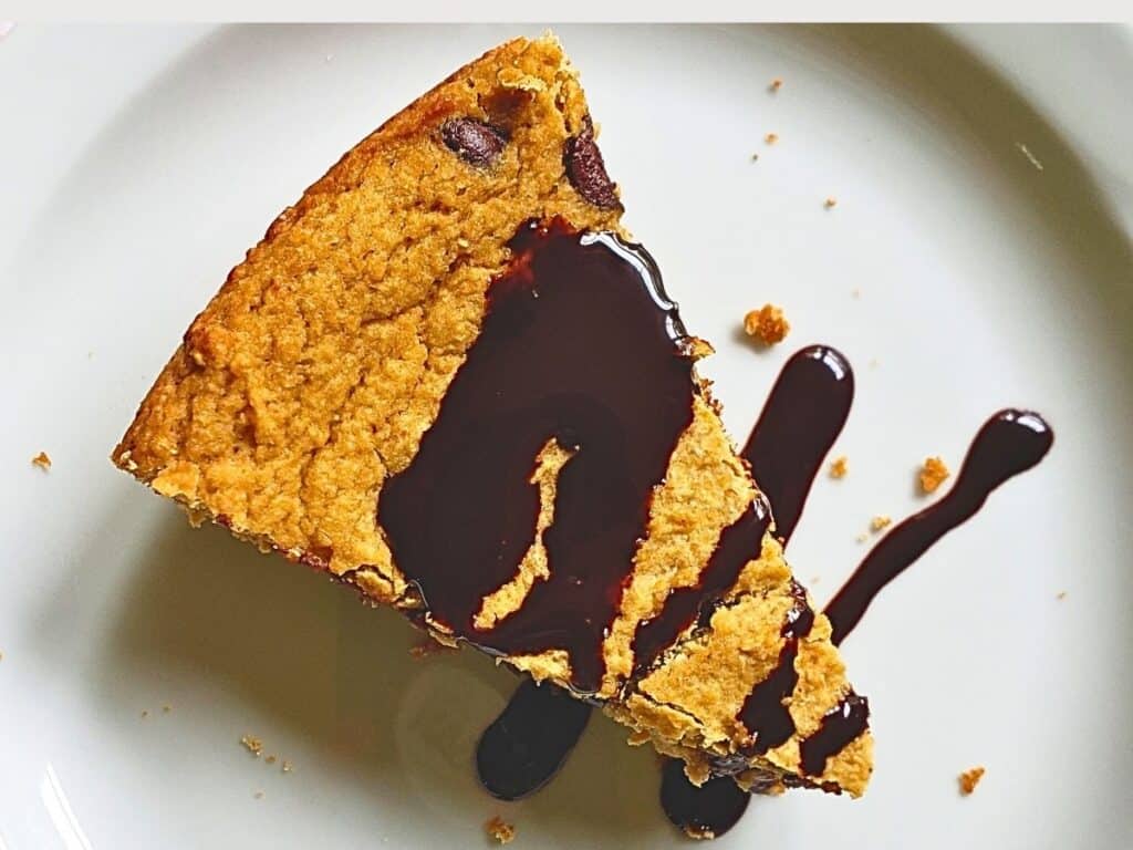 chocolate chip cookie pie on a plate drizzled with hot fudge