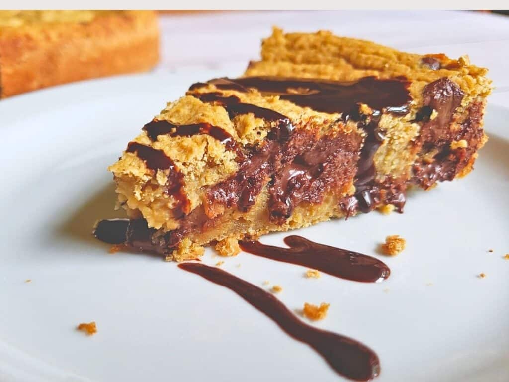 a slice of chocolate chip cookie pie drizzled with hot fudge