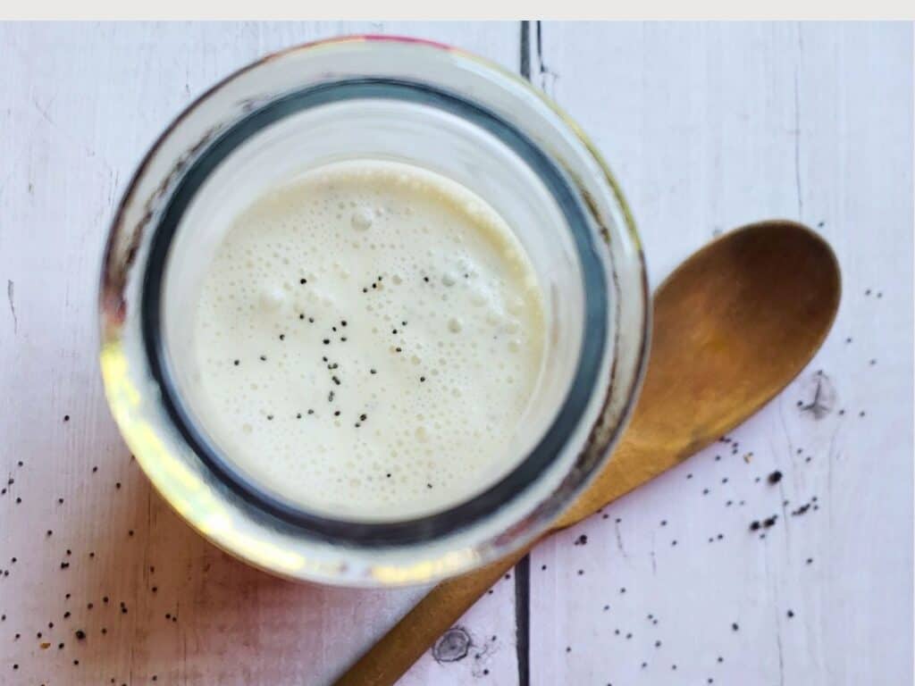 poppyseed dressing in a glass jar with a wooden spoon