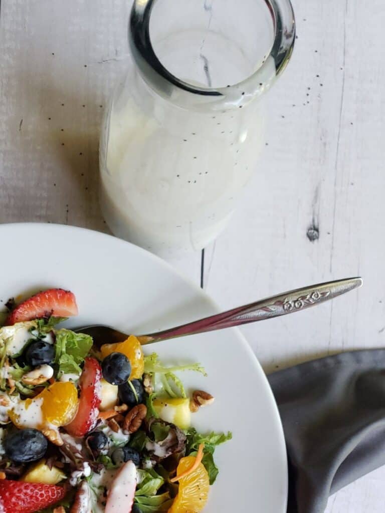 poppyseed dressing in a bottle next to a strawberry poppyseed salad