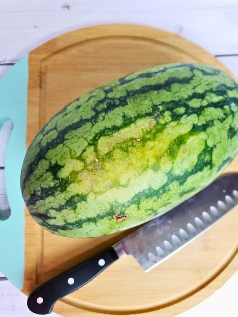 watermelon on a cutting board with a knife