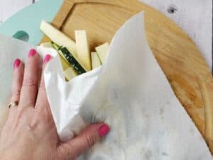 a hand with a paper towel drying cut zucchini